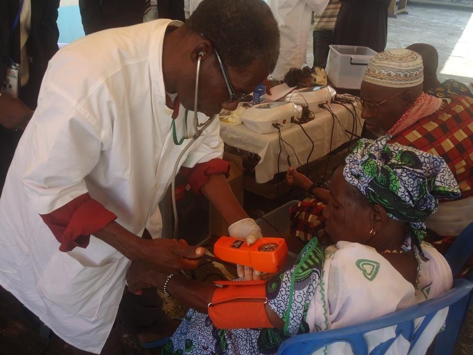 A volunteer doctor checking an older woman's blood pressure at a free health day